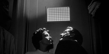 Movie still from “Invasion of the Body Snatchers” (1956), directed by Don Siegel – A man and a woman looking at each other in front of a window; Close Up shot, Low angle