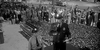 Movie still from “Invasion of the Body Snatchers” (1956), directed by Don Siegel – An old photo of a man in a police uniform; Wide shot, High angle