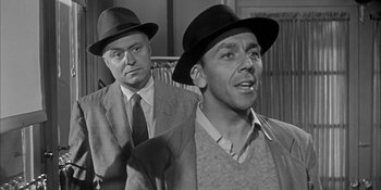 Movie still from “Invasion of the Body Snatchers” (1956), directed by Don Siegel – Two men in hats and ties are looking at the camera; Medium shot, Over the shoulder angle