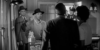 Movie still from “Invasion of the Body Snatchers” (1956), directed by Don Siegel – An old photo of a man wearing a hat; Medium shot, Over the shoulder angle