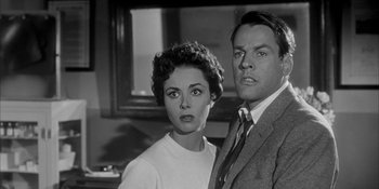 Movie still from “Invasion of the Body Snatchers” (1956), directed by Don Siegel – A man and a woman standing next to each other in a room; Close Up shot, Low angle