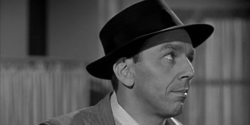 Movie still from “Invasion of the Body Snatchers” (1956), directed by Don Siegel – A black and white photo of a man wearing a hat; Close Up shot, Over the shoulder angle