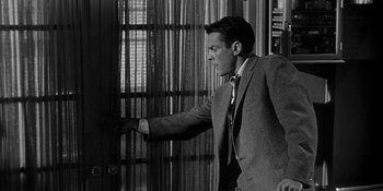 Movie still from “Invasion of the Body Snatchers” (1956), directed by Don Siegel – A black and white photo of a man in a suit and tie; Medium shot, Low angle