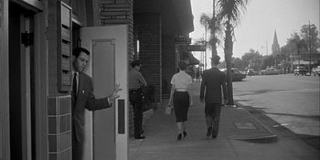 Movie still from “Invasion of the Body Snatchers” (1956), directed by Don Siegel – A black and white photo of people walking down a sidewalk; Medium shot, Over the shoulder angle