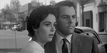 Movie still from “Invasion of the Body Snatchers” (1956), directed by Don Siegel – A man and a woman standing next to each other in front of a building; Close Up shot, Low angle