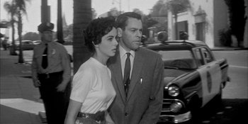 Movie still from “Invasion of the Body Snatchers” (1956), directed by Don Siegel – A man and a woman standing next to each other in front of a car; Medium shot, Low angle