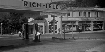 Movie still from “Invasion of the Body Snatchers” (1956), directed by Don Siegel – An old gas station on the side of the street; Extreme Wide shot, High angle