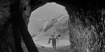 Movie still from “Invasion of the Body Snatchers” (1956), directed by Don Siegel – A man carrying a young girl through a cave; Wide shot, Low angle