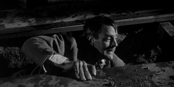 Movie still from “Invasion of the Body Snatchers” (1956), directed by Don Siegel – A black and white photo of a man climbing a wall; Close Up shot, High angle