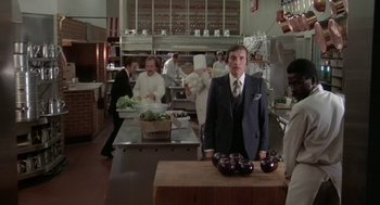 Movie still from “Invasion of the Body Snatchers” (1978), directed by Philip Kaufman – A group of people in a kitchen preparing food; Medium shot, Over the shoulder angle
