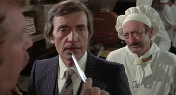 Movie still from “Invasion of the Body Snatchers” (1978), directed by Philip Kaufman – A man in a striped suit holding a knife in his mouth; Close Up shot, Over the shoulder angle