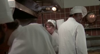 Movie still from “Invasion of the Body Snatchers” (1978), directed by Philip Kaufman – A group of people standing around in a kitchen; Medium shot, Over the shoulder angle
