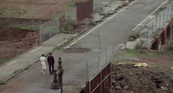 Movie still from “Invasion of the Body Snatchers” (1978), directed by Philip Kaufman – Two people are walking down the sidewalk near a fence; Extreme Wide shot, High angle