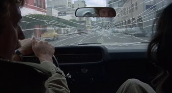Movie still from “Invasion of the Body Snatchers” (1978), directed by Philip Kaufman – A man driving a car through a shattered windshield; Medium shot, Over the shoulder angle