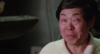 Movie still from “Invasion of the Body Snatchers” (1978), directed by Philip Kaufman – An older asian woman is smiling for the camera; Close Up shot, Low angle