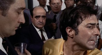 Movie still from “Investigation of a Citizen Above Suspicion” (1970), directed by Elio Petri – A group of men standing next to each other in a room; Close Up shot, Low angle