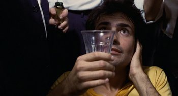 Movie still from “Investigation of a Citizen Above Suspicion” (1970), directed by Elio Petri – A man holding up a glass of water to his face; Close Up shot, Overhead angle