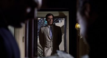 Movie still from “Investigation of a Citizen Above Suspicion” (1970), directed by Elio Petri – A man in a suit standing in front of an open door; Medium shot, Over the shoulder angle