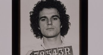 Movie still from “Investigation of a Citizen Above Suspicion” (1970), directed by Elio Petri – Black and white photograph of a young man holding a license plate; Close Up shot, Low angle