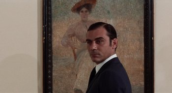 Movie still from “Investigation of a Citizen Above Suspicion” (1970), directed by Elio Petri – A man standing in front of a painting of a woman; Close Up shot, Low angle