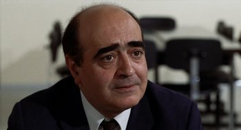 Movie still from “Investigation of a Citizen Above Suspicion” (1970), directed by Elio Petri – An older man in a suit and tie looking to his left; Close Up shot, High angle