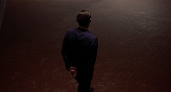Movie still from “Investigation of a Citizen Above Suspicion” (1970), directed by Elio Petri – A man in a blue suit is walking on a red floor; Extreme Wide shot, High angle