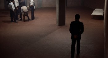 Movie still from “Investigation of a Citizen Above Suspicion” (1970), directed by Elio Petri – A man in a suit standing in an empty room; Extreme Wide shot, High angle