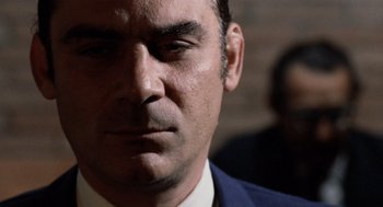 Movie still from “Investigation of a Citizen Above Suspicion” (1970), directed by Elio Petri – A person wearing a suit and tie; Close Up shot, Low angle
