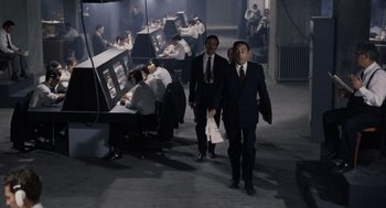 Movie still from “Investigation of a Citizen Above Suspicion” (1970), directed by Elio Petri – A group of men in suits and ties walking in a room; Wide shot, High angle