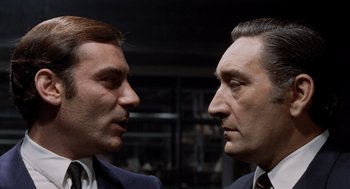 Movie still from “Investigation of a Citizen Above Suspicion” (1970), directed by Elio Petri – Two men in business suits face each other; Close Up shot, Low angle