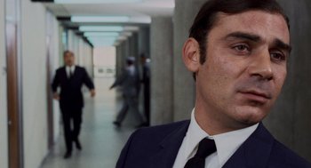 Movie still from “Investigation of a Citizen Above Suspicion” (1970), directed by Elio Petri – A man in a suit and tie in a hallway; Close Up shot, Low angle