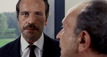 Movie still from “Investigation of a Citizen Above Suspicion” (1970), directed by Elio Petri – A person looking at a person in a mirror; Close Up shot, Over the shoulder angle