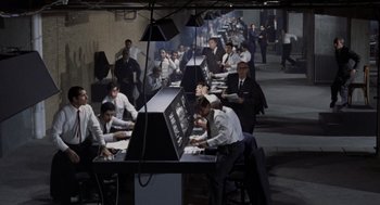 Movie still from “Investigation of a Citizen Above Suspicion” (1970), directed by Elio Petri – A group of men working on computers in a room; Wide shot, High angle