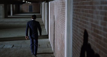 Movie still from “Investigation of a Citizen Above Suspicion” (1970), directed by Elio Petri – A man in a suit walking down a hallway; Wide shot, High angle