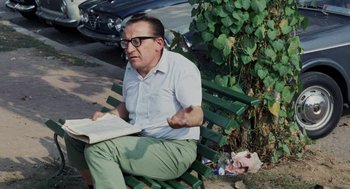 Movie still from “Investigation of a Citizen Above Suspicion” (1970), directed by Elio Petri – An older man sitting on a park bench reading a book; Medium shot, High angle