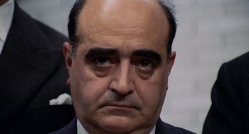 Movie still from “Investigation of a Citizen Above Suspicion” (1970), directed by Elio Petri – An older man with a bald head wearing a suit and tie; Close Up shot, High angle
