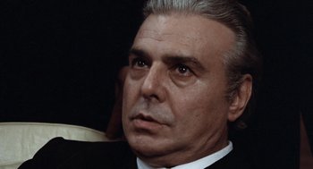Movie still from “Investigation of a Citizen Above Suspicion” (1970), directed by Elio Petri – An older man in a black suit and white shirt; Close Up shot, Low angle