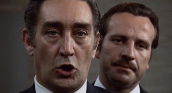 Movie still from “Investigation of a Citizen Above Suspicion” (1970), directed by Elio Petri – Two men in business suits are looking at the camera; Close Up shot, Low angle