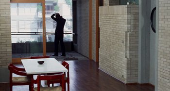 Movie still from “Investigation of a Citizen Above Suspicion” (1970), directed by Elio Petri – A man standing in front of a window in a room; Wide shot, High angle