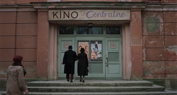 Movie still from “Invincible” (2001), directed by Werner Herzog – A man and a woman are standing in front of a building; Wide shot, Low angle