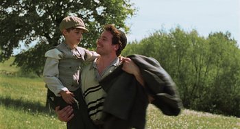 Movie still from “Invincible” (2001), directed by Werner Herzog – A man and a boy in a field with trees in the background; Medium shot, Low angle