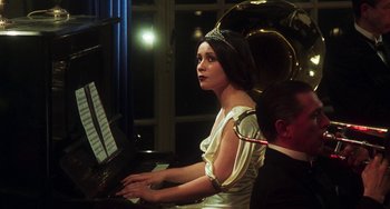 Movie still from “Invincible” (2001), directed by Werner Herzog – A woman sitting at a piano with a man standing next to her; Medium shot, Over the shoulder angle