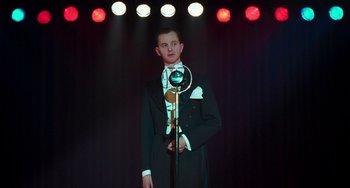 Movie still from “Invincible” (2001), directed by Werner Herzog – A man in a tuxedo standing in front of a microphone; Medium shot, Low angle