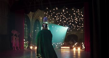 Movie still from “Invincible” (2001), directed by Werner Herzog – A man in a green robe is standing in front of lights; Extreme Wide shot, Over the shoulder angle