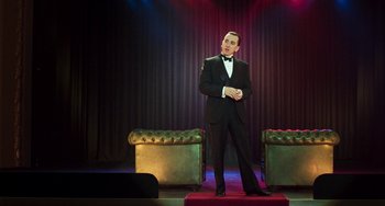 Movie still from “Invincible” (2001), directed by Werner Herzog – A man in a tuxedo standing in front of two green chairs; Wide shot, Low angle