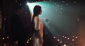 Movie still from “Invincible” (2001), directed by Werner Herzog – A woman standing in front of a microphone in front of an audience; Medium shot, Over the shoulder angle