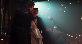 Movie still from “Invincible” (2001), directed by Werner Herzog – A man and a woman in a black suit talking to a man in a black suit; Medium shot, Low angle