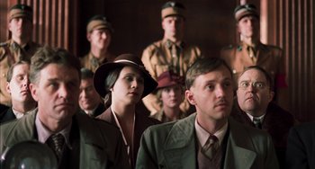 Movie still from “Invincible” (2001), directed by Werner Herzog – A group of men and women standing next to each other; Medium shot, Over the shoulder angle