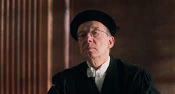 Movie still from “Invincible” (2001), directed by Werner Herzog – An older man wearing a hat and glasses; Close Up shot, Over the shoulder angle