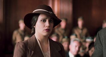 Movie still from “Invincible” (2001), directed by Werner Herzog – A woman wearing a brown hat in front of a group of people; Close Up shot, Over the shoulder angle